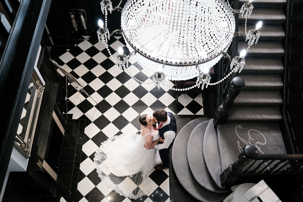 Bride and groom kissing under chandelier, Swynford Manor wedding